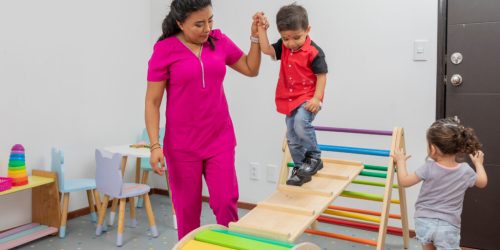 Pediatric doctor giving therapy to a child in the playground of her medical office